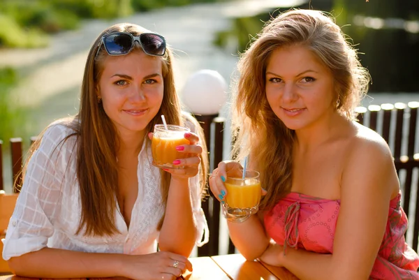 Dvě šťastné ženy pít pomerančový džus — Stock fotografie