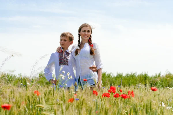 Teenage sister and little brother together on summer wheat fields — Stok fotoğraf