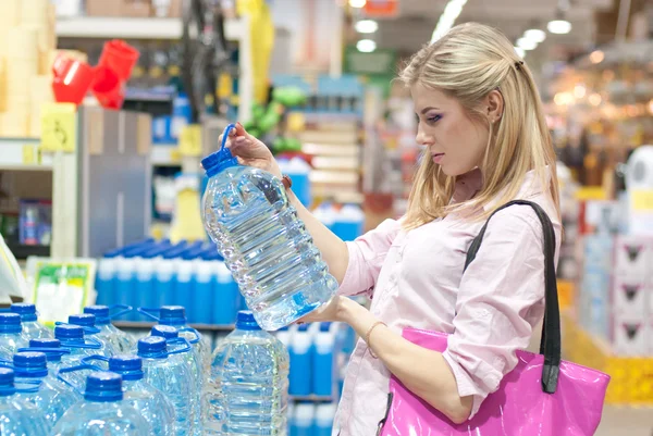 Kvinna köper en flaska vatten i butik — Stockfoto