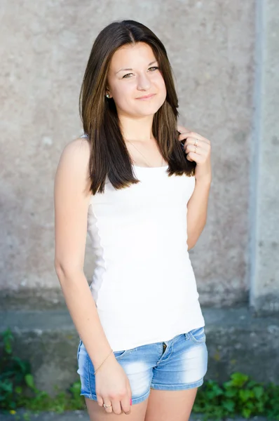 Young happy teenage girl standing at gray wall — Stock Photo, Image