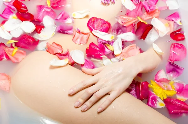 Linda senhora tomando um banho com pétalas de flores — Fotografia de Stock