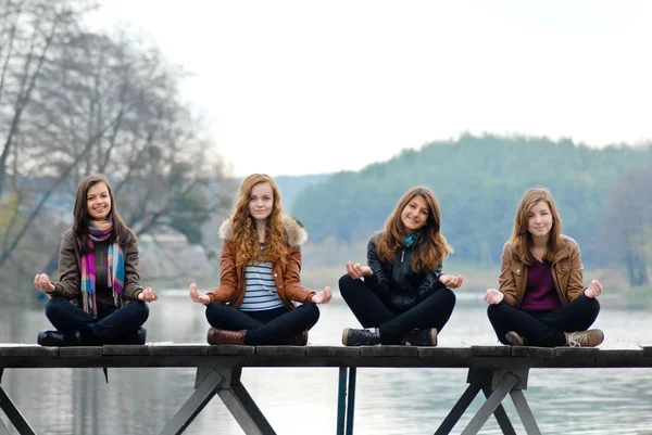 Quattro ragazze della scuola sul ponte sul fiume — Foto Stock