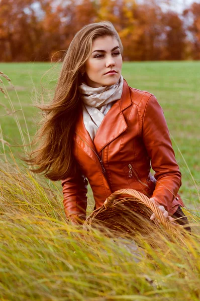 Schöne junge Frau sitzt im hohen Gras an einem windigen Herbsttag — Stockfoto