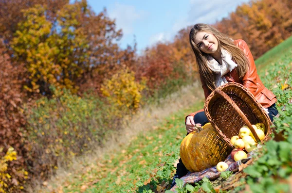 Happy young woman with basket of fresh apples