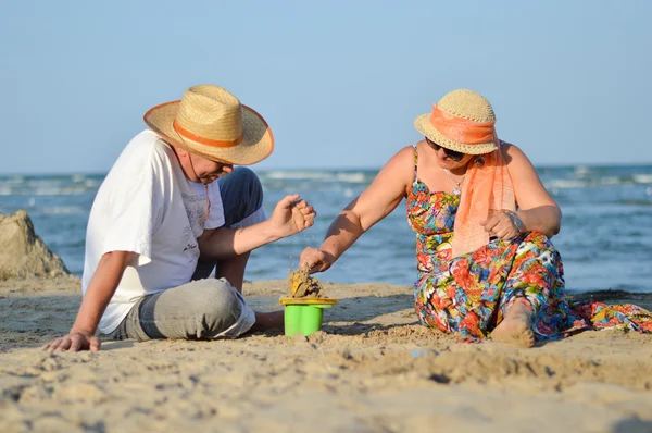 Feliz pareja madura jugando en la orilla del mar en la playa de arena — Foto de Stock