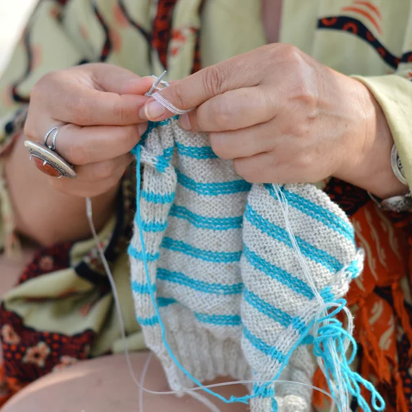 Happy mature woman sitting on beach and knitting — Stock Photo, Image