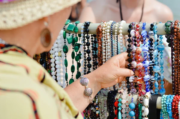 Frau wählt Schmuck in Reihe von Halsketten und Armbändern — Stockfoto