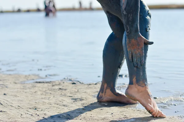 Mujer aplicando barro azul mineral en las piernas en el lago Sivash — Foto de Stock