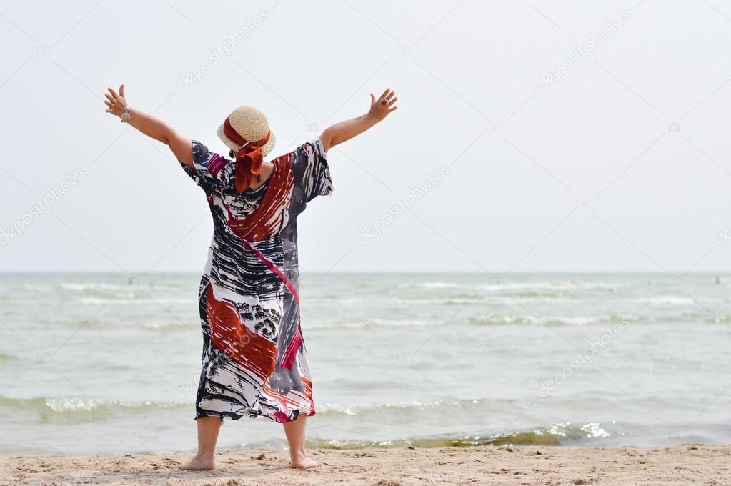 Happy mature woman enjoying breeze on seashore