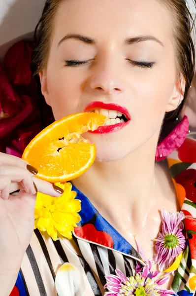 Woman relaxing in milk bath with flowers — Stock Photo, Image