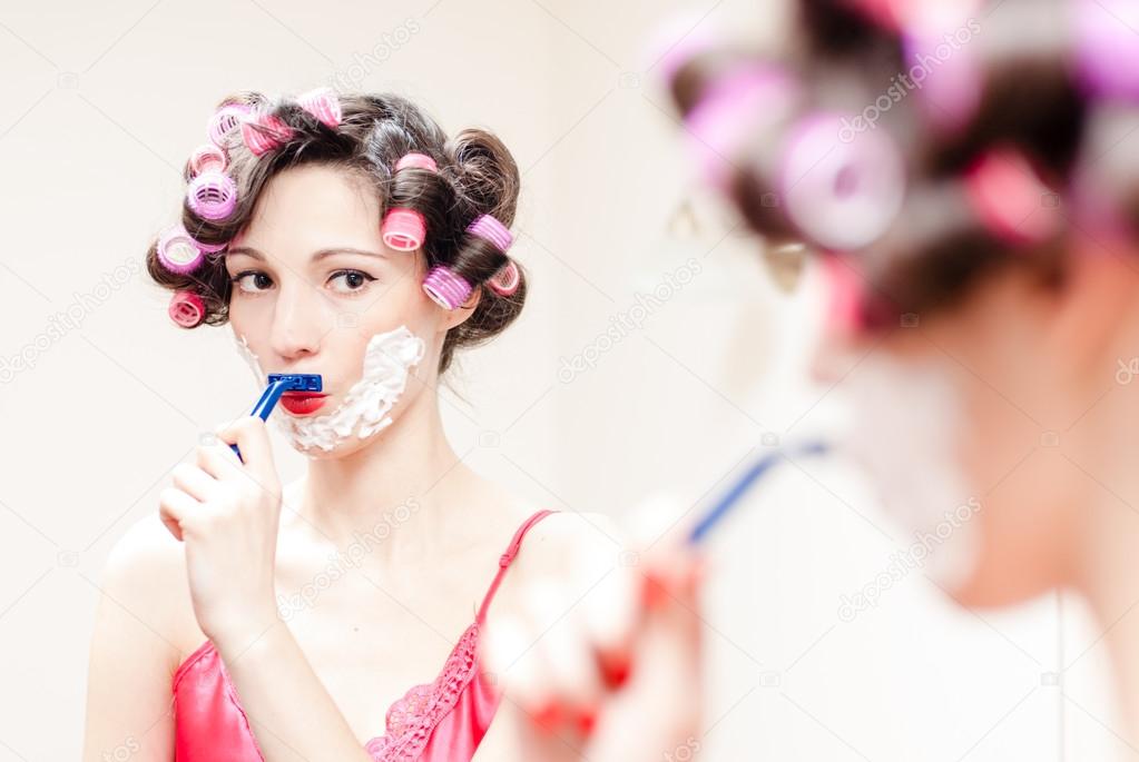 Young beautiful pinup woman shaving mustache with razor and foam