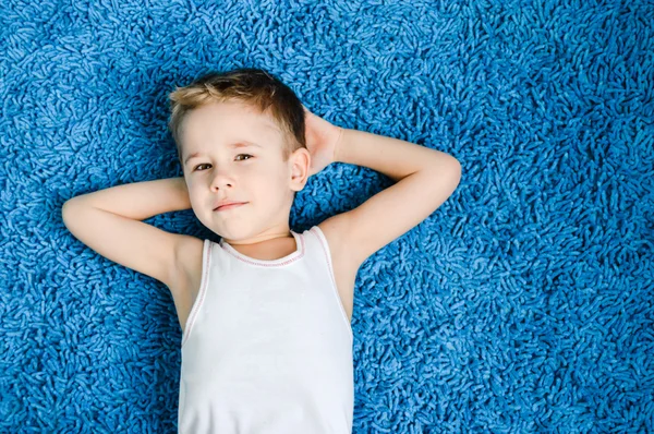 Joyeux garçon souriant enfant sur tapis bleu — Photo