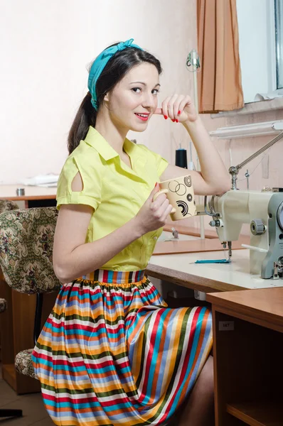 Забавная молодая женщина с швейной машинкой — стоковое фото