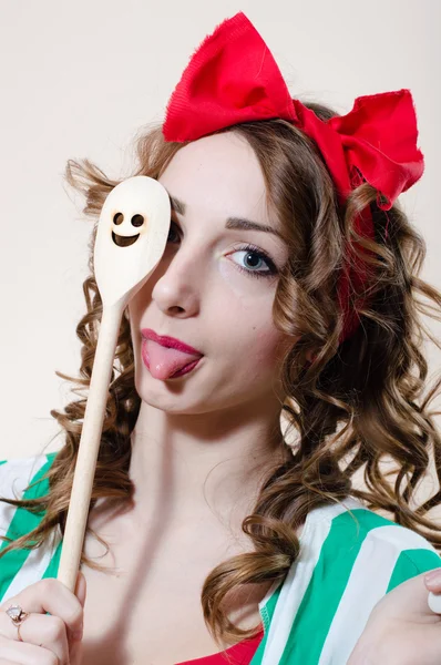 Funny pinup woman showing tongue abd holding kitchen ware — Stock Photo, Image