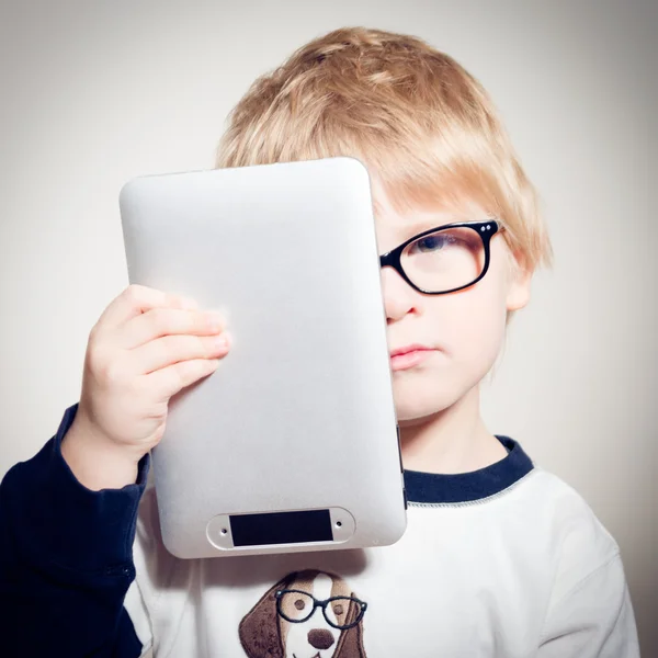 Enfant garçon dans des lunettes tenant comprimé pc — Photo