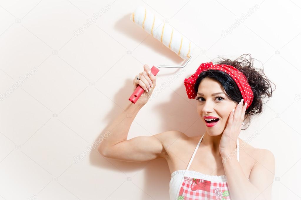 Funny charming young brunette woman beautiful pinup girl paint platen wall with roller happy smiling & looking at camera on white background closeup portrait