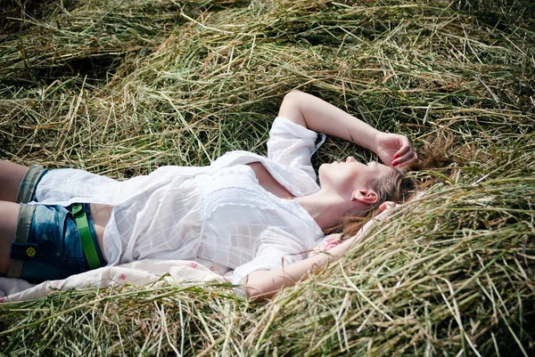 Bir yaz günü saman üzerinde yatan genç güzel kadın — Stok fotoğraf