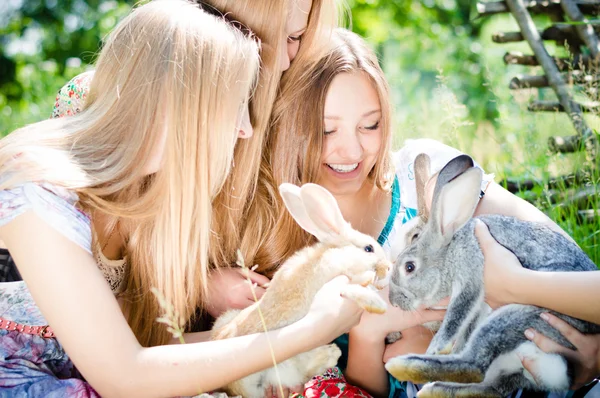 Amis avec deux lapins jouant dans le jardin — Photo