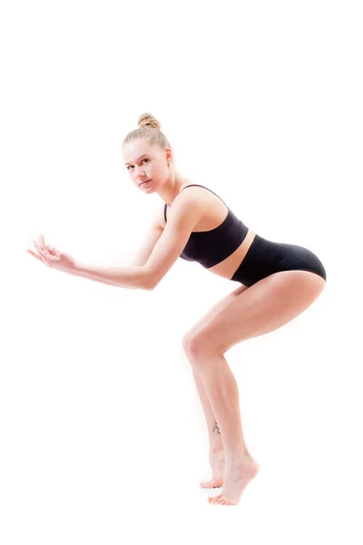 Attractive young woman athletic flexible girl in black suit looking at camera on white background — Stock Photo, Image