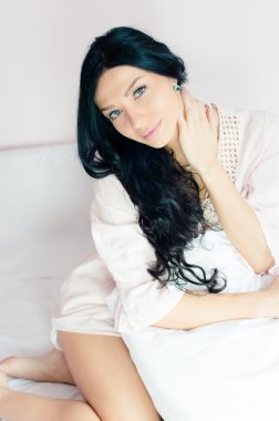 yastık holding yatakta oturan kadın