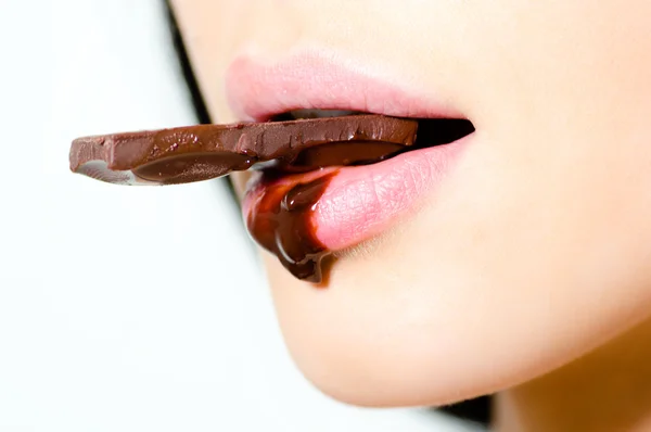 Woman eating chocolate which flows down on her lips — Stock Photo, Image