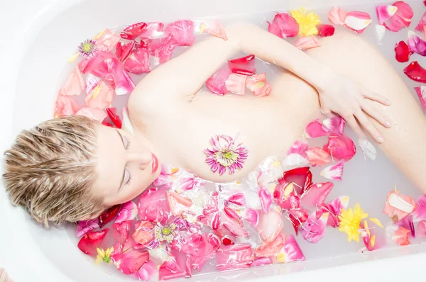 Женщина лежит в ванной с лепестками роз — стоковое фото