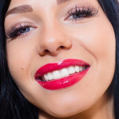 güzel çekici esmer genç kadın mavi gözlü, uzun kirpiklere, kırmızı ruj, gülümseyerek & kamera closeup resme bakarak mutlu