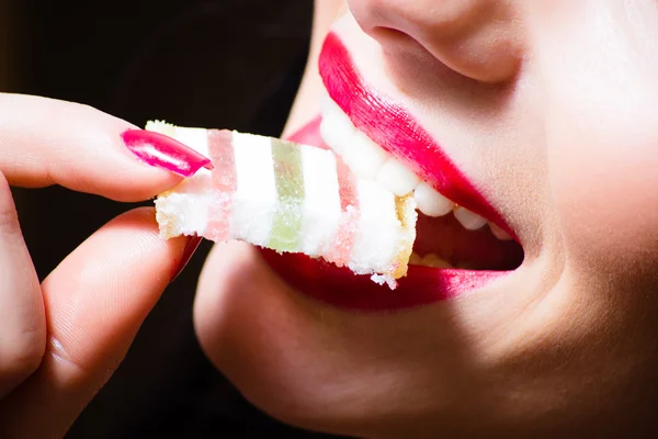 Close-up op mooie sexy vrouw met rode verleidelijke lippen en nagels bijten jujube, snoep, close-up — Stockfoto