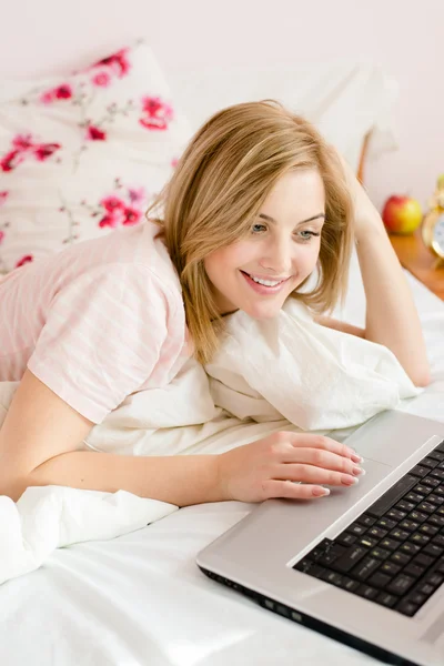 Frau im Bett arbeitet am Laptop — Stockfoto