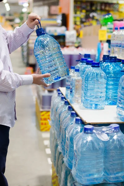 Homem selecionando ou comprando uma garrafa de bebida mineral — Fotografia de Stock
