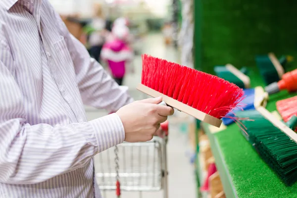 Closeup on business man selecting or choosing and buying a sweeping broom for floor or path on the DIY department shopping store background — Stock Photo, Image