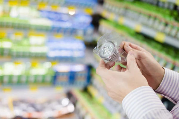 Energetické úsporné osvětlení volbou: detailní záběr na ruce drží, nebo výběrem vedl diodové žárovky lampu v hobbymarketu oddělení — Stock fotografie