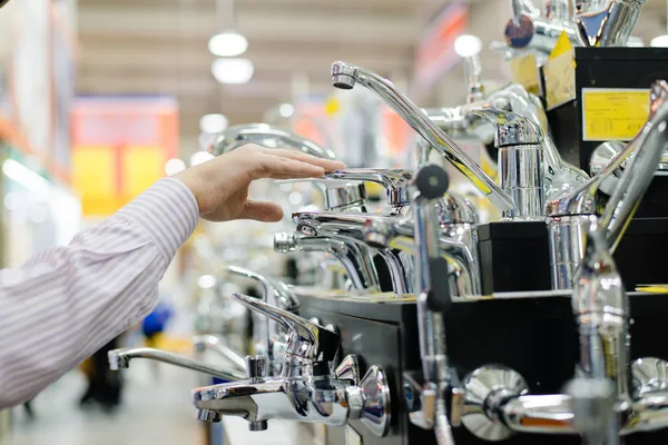 Uomo o donna d'affari che sceglie e tocca la gru del rubinetto o il rubinetto dell'acqua sull'esposizione dello scaffale di shopping del dipartimento di DIY — Foto Stock