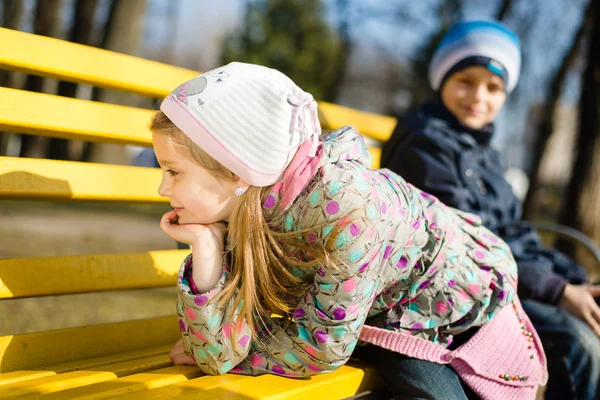 Fille et garçon assis sur un banc — Photo