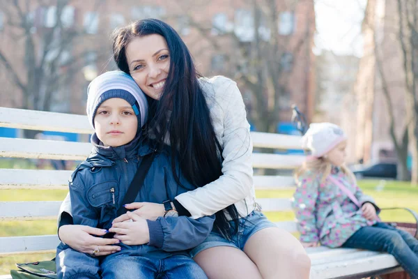 Madre sentada en el banco, sosteniendo al hijo —  Fotos de Stock