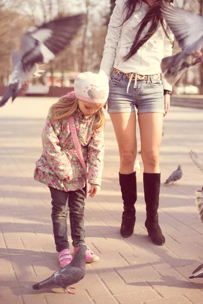 Dívka s její matkou, krmit holuby — Stock fotografie