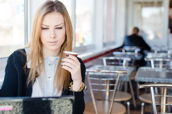 Söt kvinna som sitter på ett café, dricka kaffe och arbetar på bärbar dator — Stockfoto