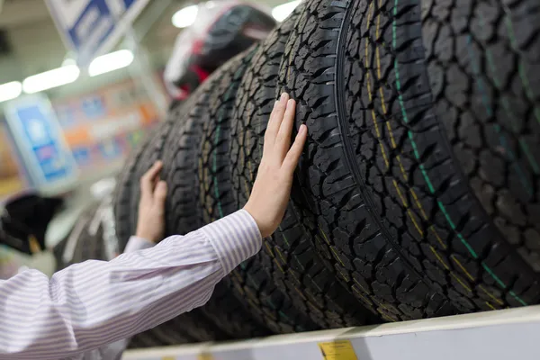 Hombre sosteniendo un neumático en la tienda — Foto de Stock