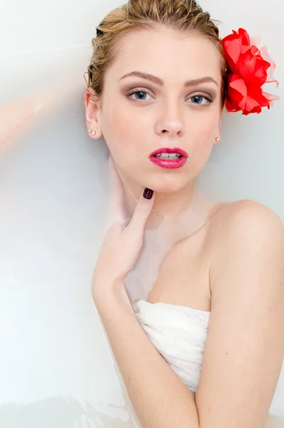 Beautiful blonde lying in bath with milk — Stockfoto