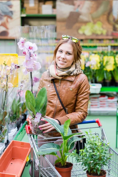 Beautiful brunette holding a pot in hands looking at camera smiling — Stock Photo, Image