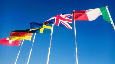 Flags of European countries flutter in the wind against the blue sky