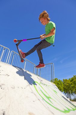 çocuk onun scooter skate Park ile atlar.