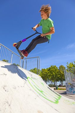 çocuk onun scooter skate Park ile atlar.