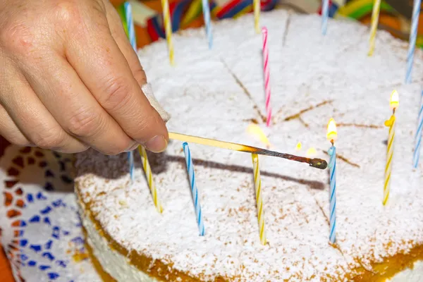 Licht de verjaardag kaarsen op de taart — Stockfoto