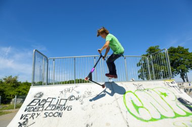 çocuk onun scooter skate Park ile atlar.