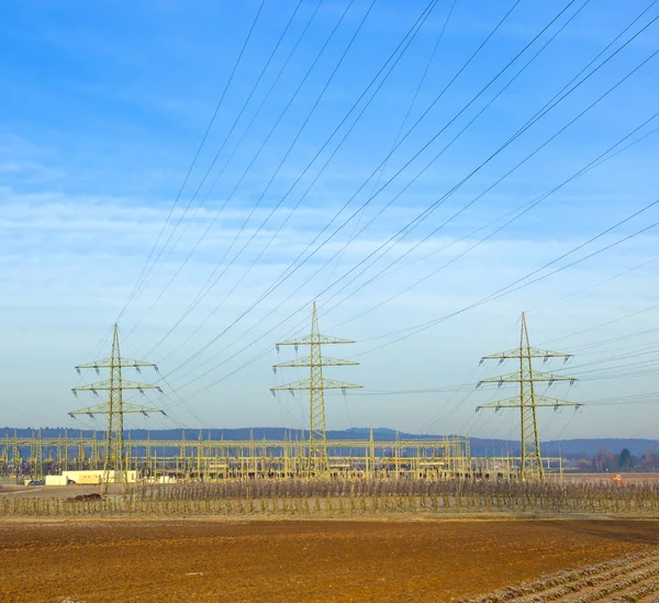 Strommast in ländlicher Landschaft mit Strohballen — Stockfoto