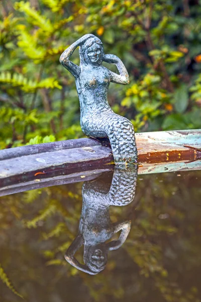 Little murmaid sitting on the edge of a metal basin and looking — Stock Photo, Image