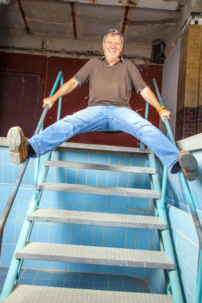 Hombre saltando por las escaleras de una vieja piscina sin agua —  Fotos de Stock