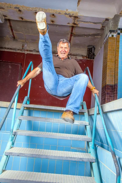 Man jumping down the stairs of an old waterless pool — Stock Photo, Image