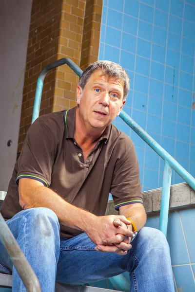 Man sitting on the stairs of an old waterless pool — Stock Photo, Image